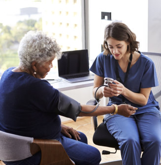 nurse checking the blood pressure of a senior woman