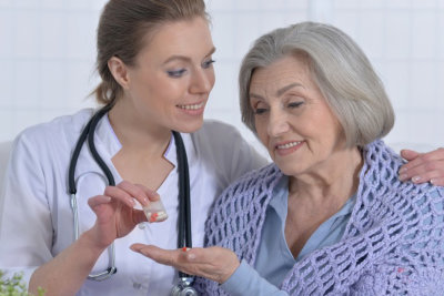 woman give elderly woman a medicine