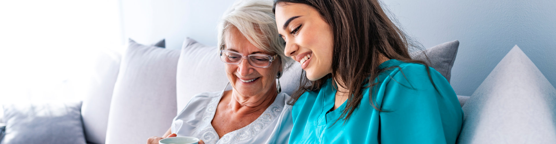 Young nurse spending time with happy elder patient in nursing home